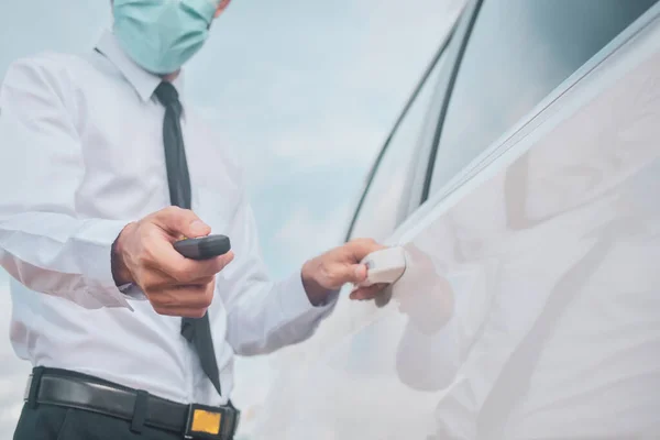 Businessman wear face mask holding key opening car door