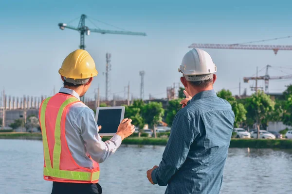 Two people worker Engineer talking discussion by tablet on site building real estate construction