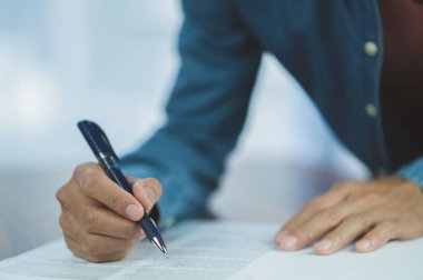 İş adamı, iş anlaşması ortaklığı ve yasal belge kavramını temsil eden resmi sözleşme belgesini masa başında imzaladı.