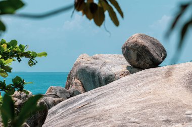 Sıcak ve güneşli bir günde mavi okyanus, gökyüzü, kayalar ve yeşil çalılar Tayland manzarası