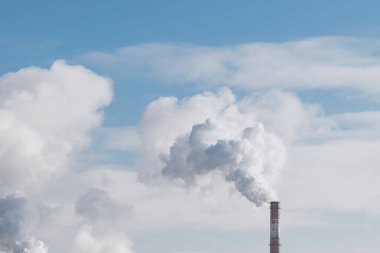 Dünya kirliliği kavramı. Fabrika bacası mavi gökyüzü arka planındaki borudan duman üflüyor kış boyunca