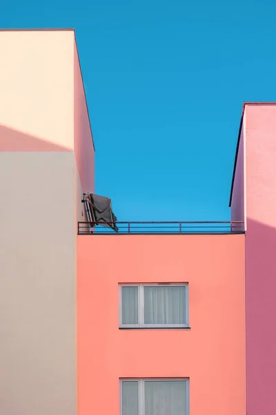 Ayrıntılı apartman dairesi rengarenk ve üzerinde açık mavi gökyüzü arka planında balkon ve güneş çatısı olan pembe, mor ve beyaz dairenin minimalist dış görünüşü