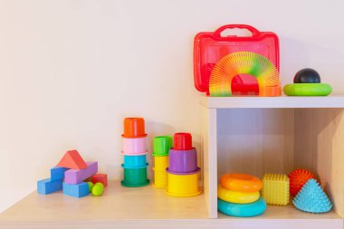 Çeşitli şekillerde ve renkli çocuk oyuncakları raflarda. Kopyalama alanı olan bej duvar