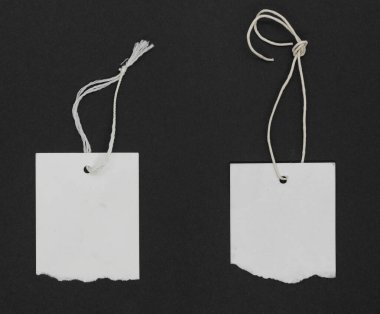 Siyah grunge kağıt arka planında yırtık beyaz kağıt etiketleri ya da iplik kravatlı etiketler. Kopyalama alanı olan beyaz etiketler