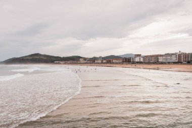 Dalgalar halinde sörfçüler. Sörfçüler ve dalgalar sahile çarpıyor. Havadan deniz manzaralı suda yüzenler. Aktif yaşam tarzı. Olağanüstü bir spor. Uçurumlar ve sörfçülerle güzel bir deniz manzarası. Boşluk kavramı.