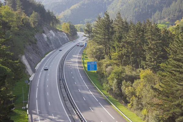 Dağlarda yol işaretleri ve arabalarla otoyol. Sonbaharda manzara eğrisi. Ulaşım ve trafik kavramı. Vadideki otoyol, Bask bölgesi. Güzel manzaralı bir trafik yolu. Avrupa 'da turizm. 