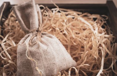 Çuval bezini dolduruculu bir kutuya koy. Noel hediyesi kutusu. Talaşlı el yapımı vintage çanta. Eski moda bir konteynır ve hediye. Süslü süprizlerle örülmüş bir çanta. Tatil dekorasyonu.