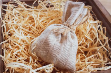 Çuval bezini dolduruculu bir kutuya koy. Noel hediyesi kutusu. Talaşlı el yapımı vintage çanta. Eski moda bir konteynır ve hediye. Süslü süprizlerle örülmüş bir çanta. Tatil dekorasyonu.