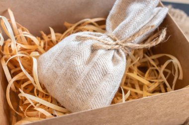 Çuval bezini dolduruculu bir kutuya koy. Noel hediyesi kutusu. Talaşlı el yapımı vintage çanta. Eski moda bir konteynır ve hediye. Süslü süprizlerle örülmüş bir çanta. Tatil dekorasyonu.