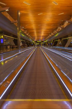 Doha, Katar - 02.20.2021: Uluslararası havaalanı Doha, Katar 'da boş bir yürüyüş yolu. Perspektif olarak hareket eden kaldırım. Havaalanı içi. Karantinada seyahat edin. Havaalanındaki geçiş bölgesi. İnsanlar olmadan taşıyıcı taşınıyor.