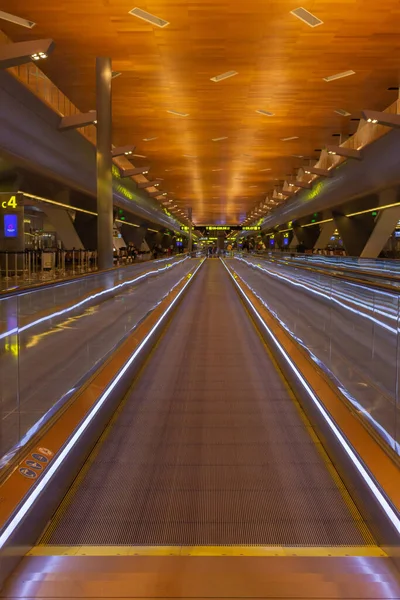 Doha, Katar - 02.20.2021: Uluslararası havaalanı Doha, Katar 'da boş bir yürüyüş yolu. Perspektif olarak hareket eden kaldırım. Havaalanı içi. Karantinada seyahat edin. Havaalanındaki geçiş bölgesi. İnsanlar olmadan taşıyıcı taşınıyor.
