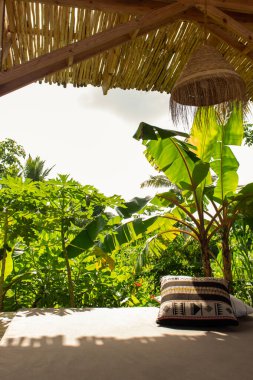 Yastıklı dinlenme yeri olan tropik bir tatil köyü. Bahçeli ve verandalı bir tatil evi. Boş egzotik bir tatil köyü. Lüks villa açık havada. Rahatlamak ve rahatlamak için ideal bir yer. Yaz yolculuğu konsepti.