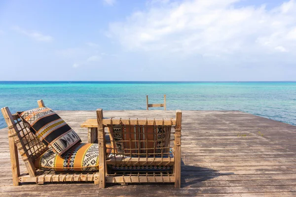 Two lounge chairs on wooden pier. Empty tropical resort. Pair of deck chairs with pillows on tropical beach. Luxury villa outdoor. Idyllic place for leisure and relax. Chilling at beach concept. African seascape.