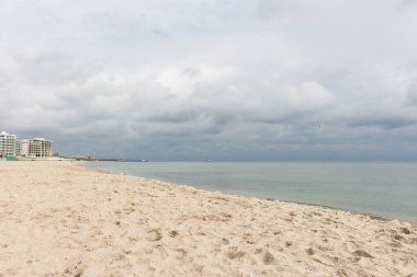 Fırtınadan önce kumsal boştu. Dramatik bulut manzarası. Sonbahar deniz manzarası. Deniz kenarında sakin bir hava var. Denizde tatiller.