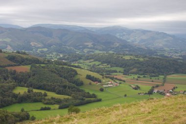 Pirenes dağlarındaki köyün havadan görünüşü. Dağların manzarası, Fransa. Yeşil tepeleri ve çiftliği olan bir kırsal. Fransız vilayetinde seyahat et. Camino de Santiago manzarası. Dağlar, tarlalar, köy, insansız hava aracı manzaralı. Yaz tatilleri. 