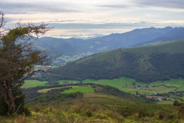 Pirenes dağlarındaki köyün havadan görünüşü. Dağların manzarası, Fransa. Yeşil tepeleri ve çiftliği olan bir kırsal. Fransız vilayetinde seyahat et. Camino de Santiago manzarası. Dağlar, tarlalar, köy, insansız hava aracı manzaralı. Yaz tatilleri. 