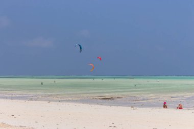 Tropik sahilde uçurtma sörfü, alçak gelgit. Denizde uçurtma sörfçüleri. Uçurtma sörflü Hint Okyanusu, Zanzibar, Paje plajı. Aktif insanlar konsepti. Afrika 'da yaz tatili. Olağanüstü spor konsepti. Parasailing sporu. 