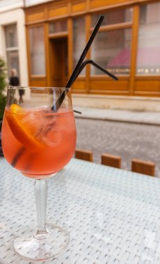 Orange cocktail with ice and two straws.  Aperol spritz cocktail on table. Drinks in outdoor bar. Summer party background. Cool alcoholic cocktails. Refreshing aperitif. Sweet cocktail in street cafe. Alcoholic drinks concept.