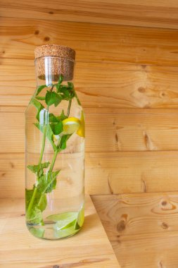 Bir şişe taze limonata. Naneli, limonlu ve limonlu bir şişe. Detoks kokteyli. Sağlıklı antioksidan içeceği. Bitki çayı. Nane yapraklı ve limon dilimli soğuk su. Yaz içkileri. Tazeleyici kavram. 