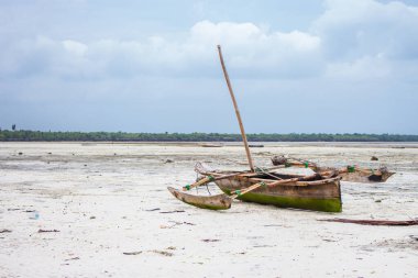 Hint Okyanusu 'nda dalgaların çekildiği ahşap tekne. Kumsalda beyaz kumlu bir balıkçı teknesi. Tropik adanın kıyı şeridi. Zanzibar 'ın göletinde bir gemi. Tropikal cennette yaz tatili. 