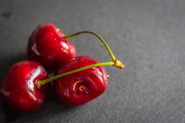 Olgun kirazlar kara tahtada. Masada sulu kirazlar var. Kiraz meyveleri. Yaz hasadı konsepti. Taze meyve. Vitamin ve içecek konsepti. Sağlıklı çiğ tatlı. Tatlı diyet. 