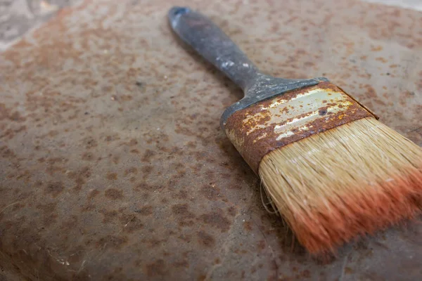 Dirty vintage brush on rusty background. Old paintbrush on grunge background with copy space. Draw tool. Painting art concept. House renovation concept. Aged hand brush. Rustic housework.