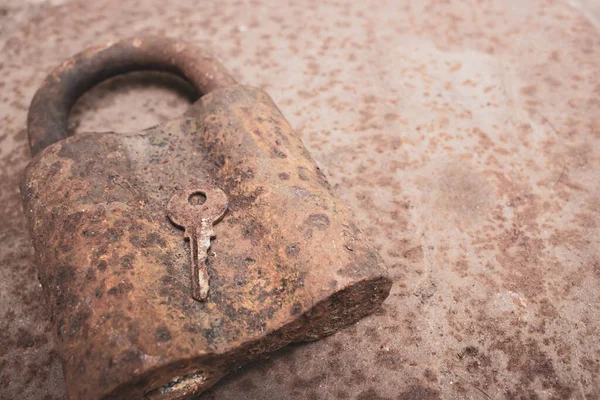 Old rusty key and lock. Vintage door padlock with key. Antique key on weathered background. Security and safety concept. Aged iron key and padlock. House protection concept.