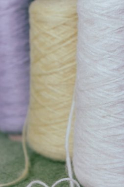 Alpaka yünü ve ipeğin çeşitli renkleri. Çok renkli iplik konileri. Sıraya dizilmiş yün iplikler. Mavi, beyaz, sarı ve gri yün sıra. Örgü hobisi. İplik parçaları. Örgü örmek için parlak yün. Canlı iplik topları.