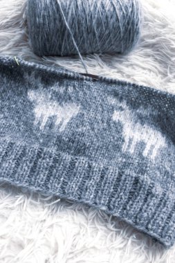 Beyaz ekose üzerinde geyik desenli gri örgü. Örgü süveter içinde rahat bir geyik süsü. İskandinav örgü deseni. Örgü moda. Yün, ahşap örgü iğnelerinde işe yarar. Komik geyik stili.