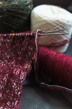 İplik yumağıyla örülmüş çoraplar. Örgü iğnelerinde kırmızı, yeşil ve beyaz ipliklerin karışımı. Yün çorap örme işlemi. Örgü hobisi. Örgü giyme konsepti. Örgü işi geçmişi. Çoraplar için örgü deseni.