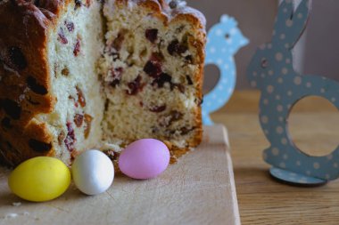 Kuru üzümlü Paskalya pastası ve masaya boyanmış yumurta. Paskalya 'da hayat. Ortodoks Yiyici kutlaması. Paskalya panettone pastası ve kuru üzümlü renkli yumurta. Bahar dini bayramı. Hristiyan geleneği. Kutsanmış Paskalya yemeği.