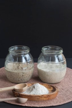 Doğal organik ekşi mayalı başlangıçlar: taze mayalanmış çavdar ve cam kavanozlarda mayalı ekmek yapmaya hazır buğday başlangıçları