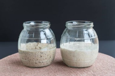 Doğal organik ekşi mayalı başlangıçlar: taze mayalanmış çavdar ve cam kavanozlarda mayalı ekmek yapmaya hazır buğday başlangıçları