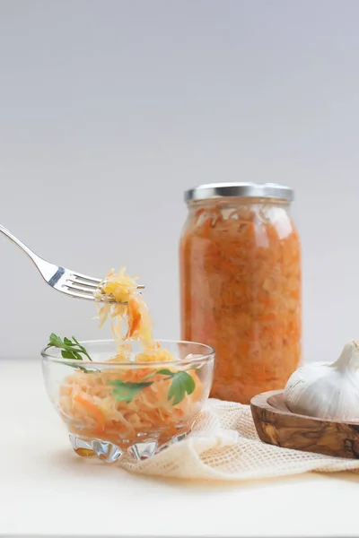 fermented food, sauerkraut or fermented cabbage with carrots in a glass jar and plate on a light background
