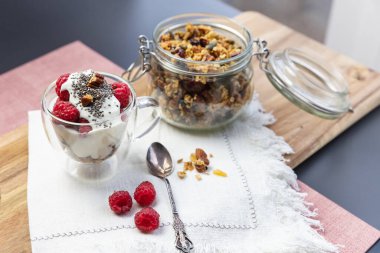 Kavanozda granola, tahtadan bir tabakta yoğurt ve böğürtlen ile servis edilir.