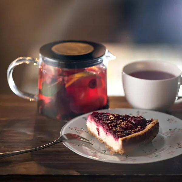 Breakfast time Food and drink. Piece of cake at white plate and herbal tea with lemon in a glass teapot. Square format or 1x1 for posting on social media