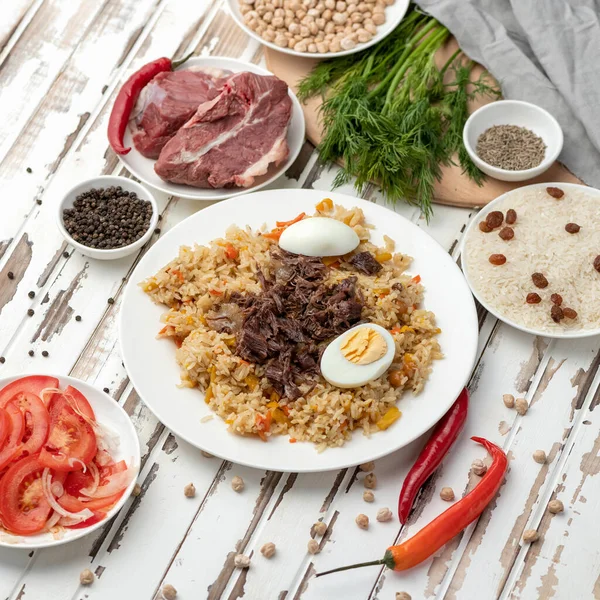 Simple plato de comida rústica. Arroz con carne, ensalada de tomate y chile picante en la mesa de la cocina de madera. Ingredientes para crear deliciosos pilaf. Sabrosa cena. Formato cuadrado para redes sociales. Vista superior — Foto de Stock