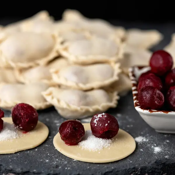 Cherry Dumplings, Cooking process. Red berry and sugar filling on rolling Raw dough circles in foreground. Close up shot. Ingredients to making delicious Convenience Food. Square format 1x1