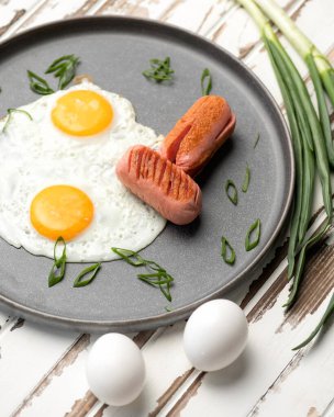 Kızarmış yumurta, sosis ve tavada yeşil soğan. Klasik Amerikan ya da İngiliz kahvaltısı.