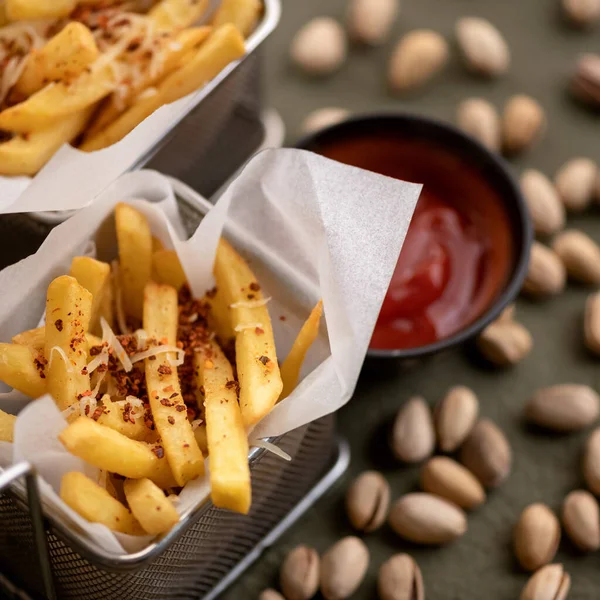 Fries or fried potatoes with ketchup and pistachios. Junk food. Soft focus, close up. Top view — Stock Photo, Image