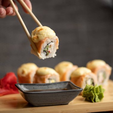 Kişi ahşap çubuklarla suşi yer, soya sosuna batırır. Asya ya da Japon yemekleri, Doğu mutfağı. Yakın çekim. Yumuşak odak