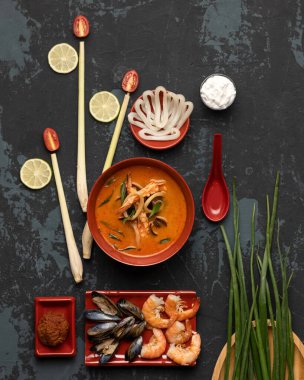 Deniz ürünleri yemeği. Karides, midye, kalamar dilimleri ve baharatlı Tom Yam çorbası. Siyah arkaplanda üst görünüm. Baharatlı doğu yemeği, Pan-Asya mutfağı.