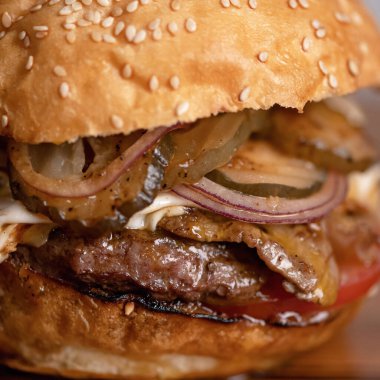 Burger, kapat. Sulu et, soğan ve domateslerden yapılmış taze hamburger. Fast food menüsü konsepti. Besleyici atıştırmalıklar ya da öğle yemeği. Klasik Amerikan yemeği. Yumuşak odak