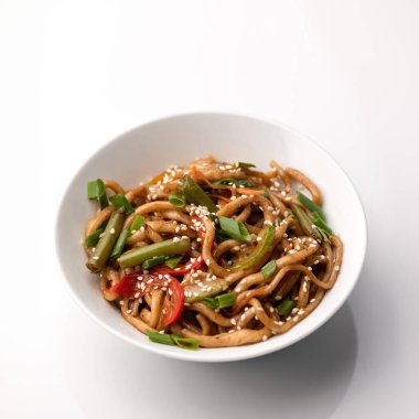 Sebzeli ve susamlı erişte ya da spagetti. Beyaz arka planda izole edilmiş vejetaryen yemek tabağı, Top view. Yenge menüsünden aperatif oryantal yemek. Yumuşak odaklanma. Pan-Asya mutfağı