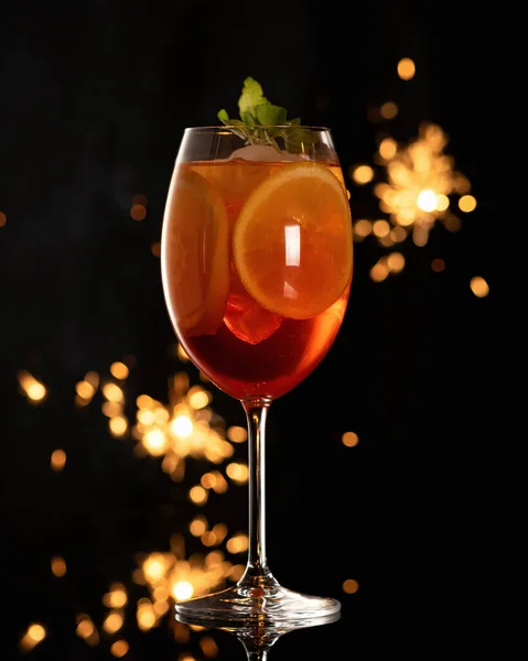 Склянка екзотичного коктейлю з льодом та апельсиновими скибочками на чорному тлі з боке з блискіток. Алкогольний напій. Вертикальний формат — стокове фото
