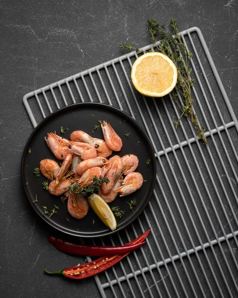 Krevety nebo krevety s citrónem a horkým chilli pepřem. Horní pohled na mořské plody desky na černém pozadí. Pikantní orientální pokrm, tradiční panasijská kuchyně — Stock fotografie