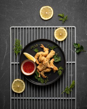 Sebzeli kızarmış karides. Deniz ürünleri konsepti. Pişmiş karides, limon ve siyah arka planda domates soslu yeşillik tabağı. Restoranda güzel servis tabağı var. Üst görünüm