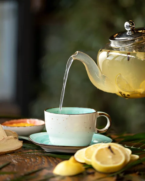 Heißer Zitronen-Ingwer-Tee aus einer gläsernen Teekanne in eine Tasse gießen. Medizinisches Vitamingetränk zur Stärkung der Immunität. Konzept der Teezeremonie. Nahaufnahme. Kopierraum — Stockfoto