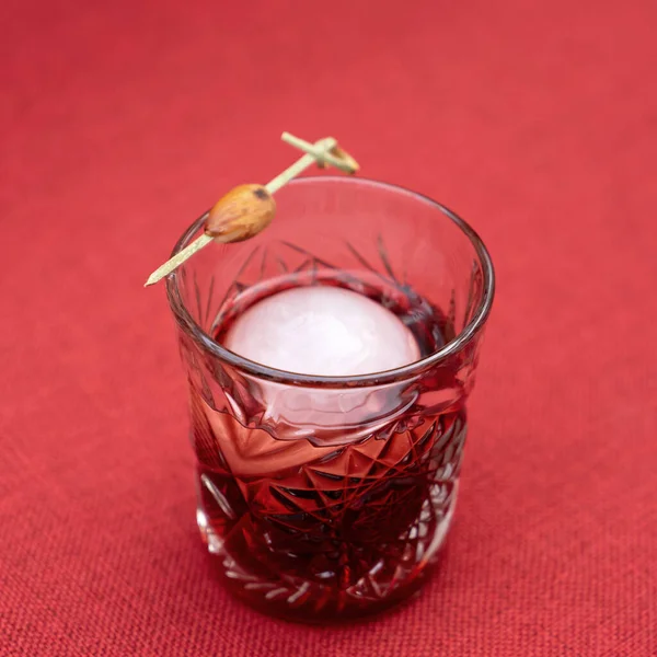 Schnapsglas mit Eis auf roter Stofftischdecke. Nahaufnahme — Stockfoto