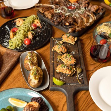 Restoranda öğle yemeği. Kızarmış et, fırında patates ve spagetti tabağı. Yürekli bir yemek. Şenlik masasında bolca lezzetli yemek var. Üst Manzara. Uzayı kopyala Yumuşak odaklanma. Web pankartı için kare biçimi